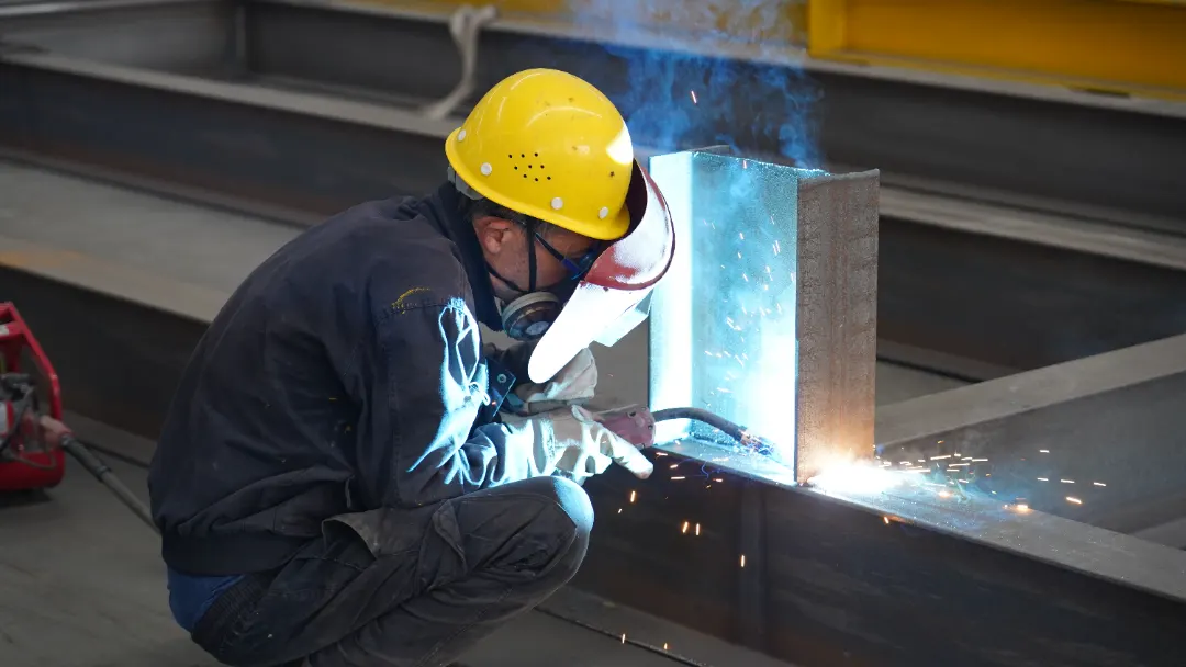 SynJect's certified welders laying a continuous weld along the flange-to-web seam of a built-up H-section beam