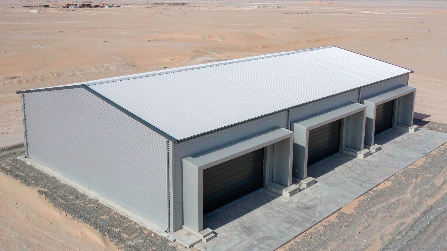 PEB steel warehouse in a UAE industrial zone with a 30 m clear span, standing-seam roof and three loading docks